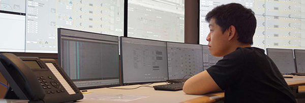 a control room operator sits in front of a bank of displays