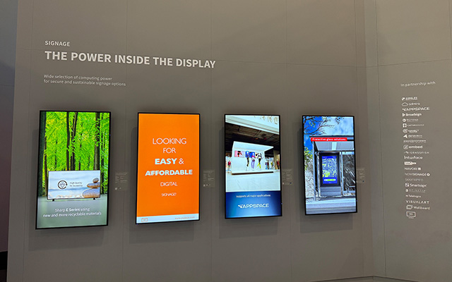 Four portrait wall-mounted digital screens show colourful content